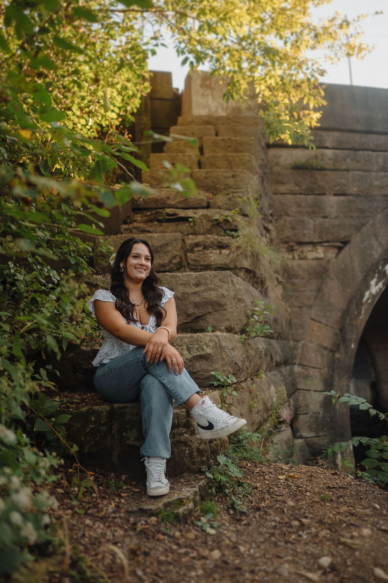 A casual portrait taken near stone steps and an archway during golden hour with soft natural lighting.