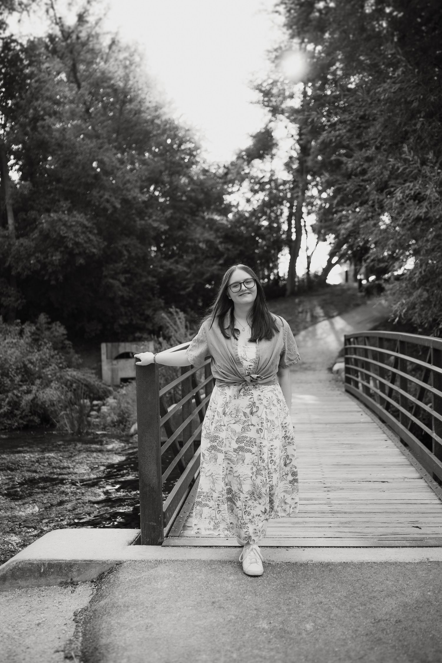 Black and white portrait on a wooden bridge with trees in the background.