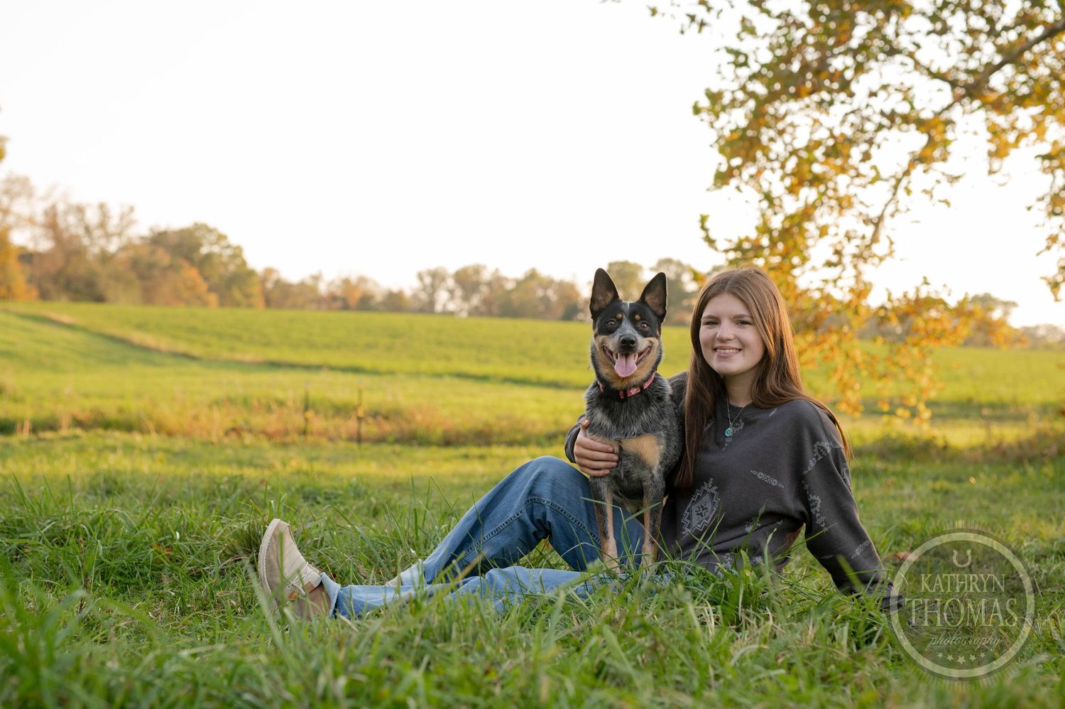 A German Shepherd and someone rest together on grassy hillside during golden hour.