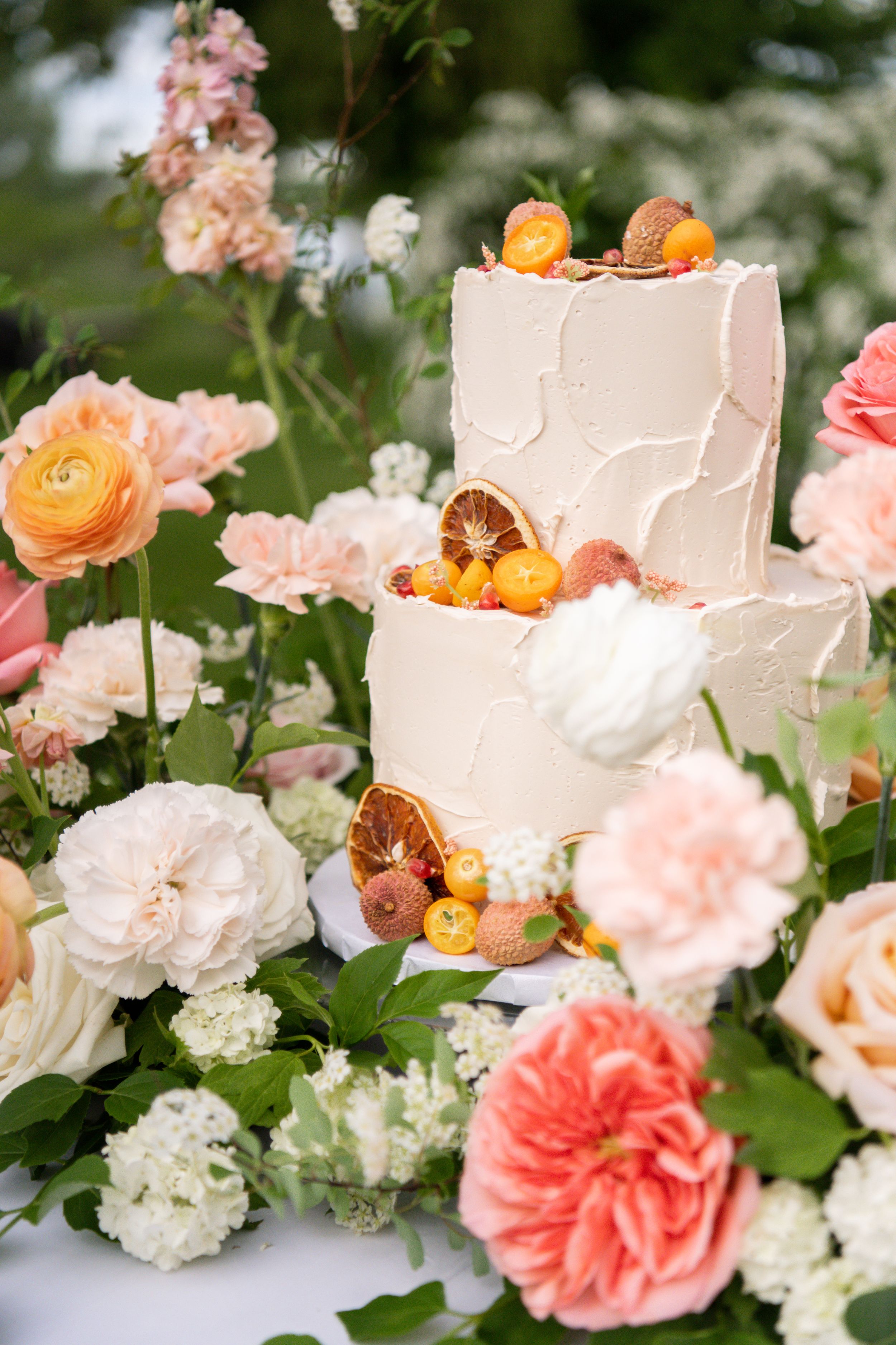 Beautiful floral arrangement with coral and peach roses alongside a white wedding cake.
