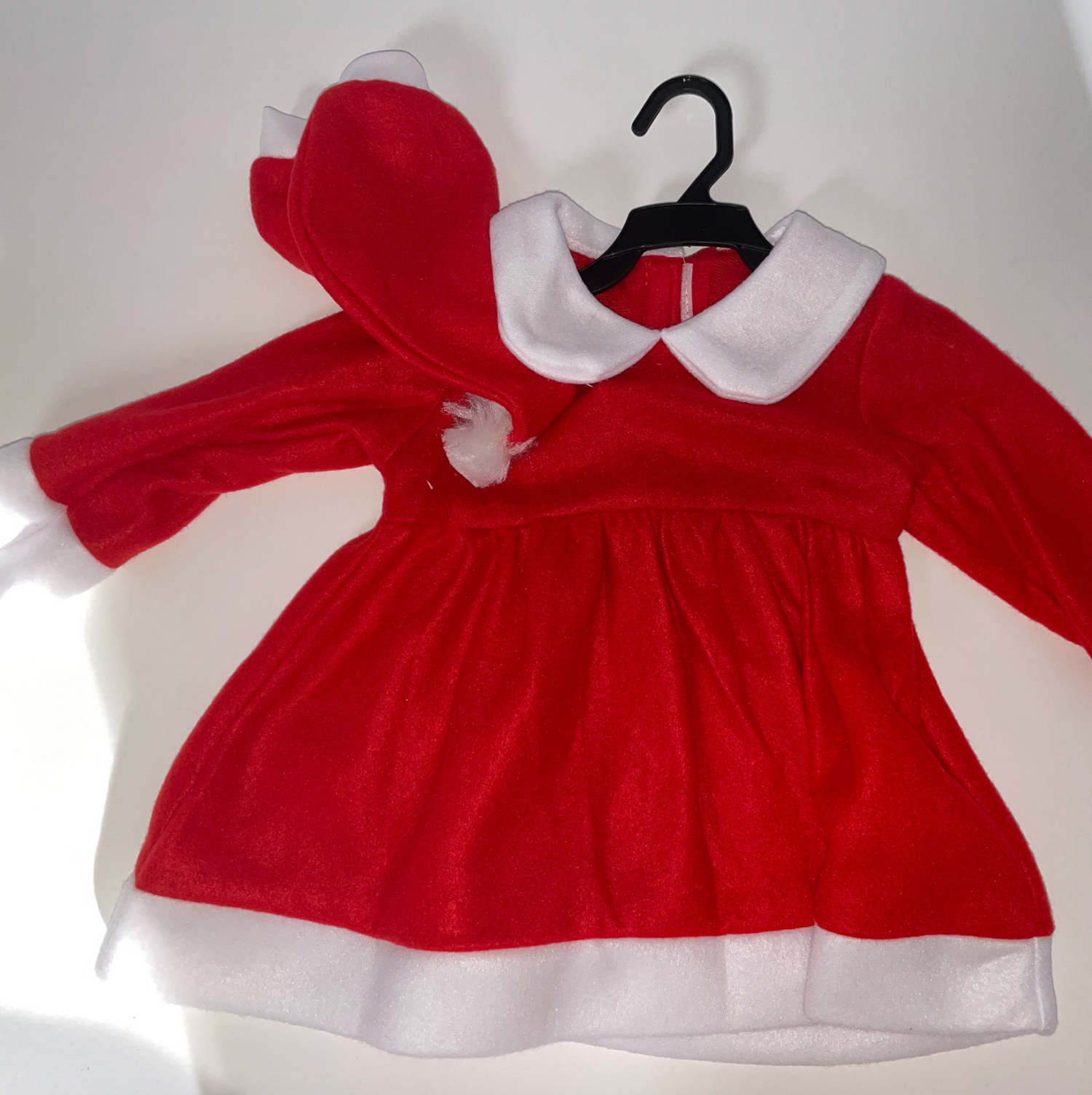 Red velvet dress with white collar displayed flat on light surface.
