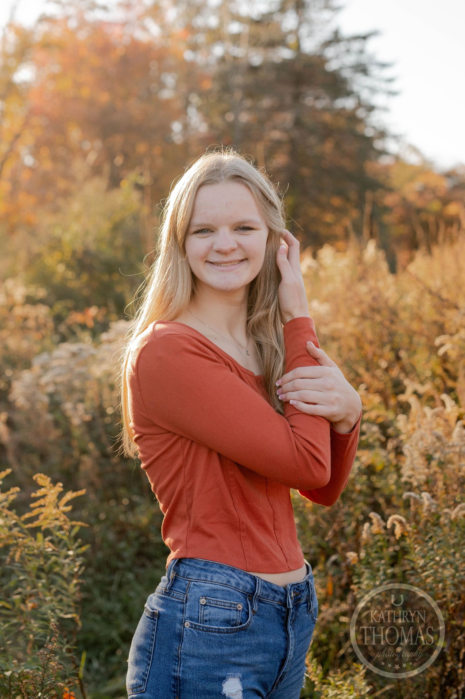 Natural light portrait in orange sweater with autumn scenery and golden hour glow.