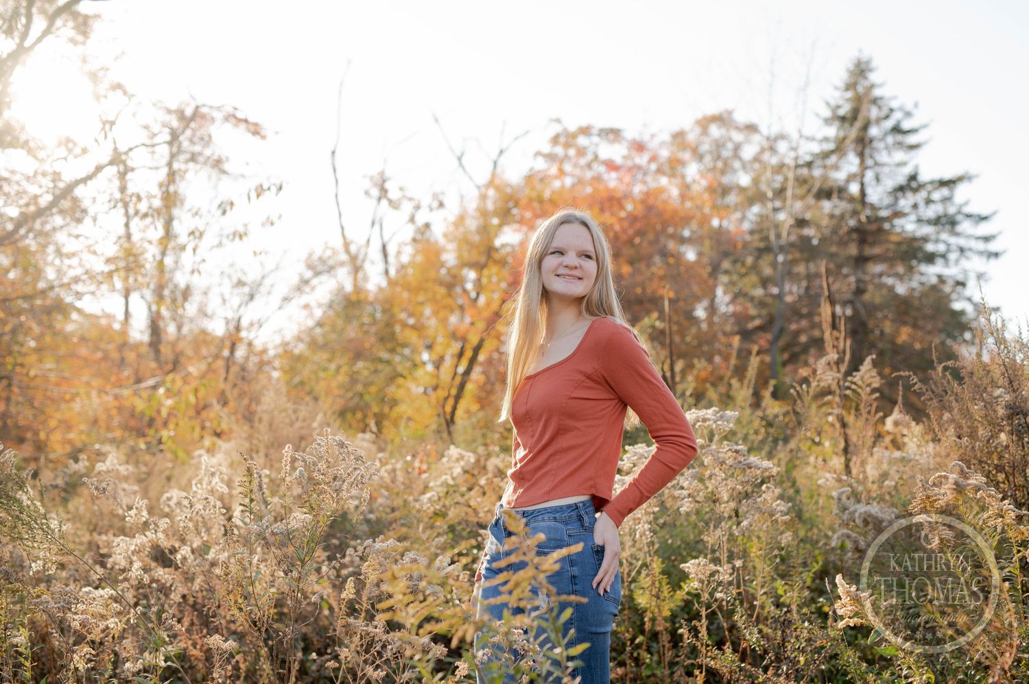 Outdoor portrait with warm autumn colors and natural light filtering through fall foliage.