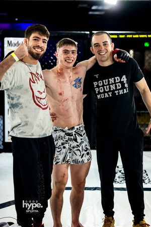 Athletes standing together after a Muay Thai competition at a professional fighting venue with venue lighting visible.