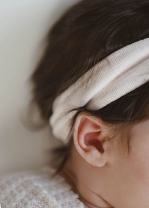 Close-up profile of sleeping newborn with white headband.