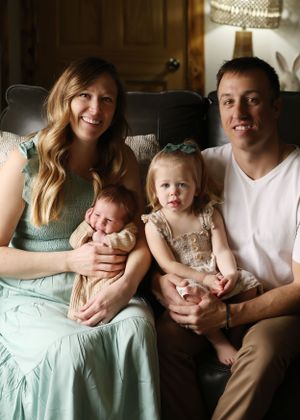 A family sits together on a couch in casual attire with mint green accents.