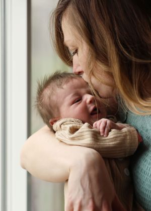 A tender family interaction captured in natural light near a window.