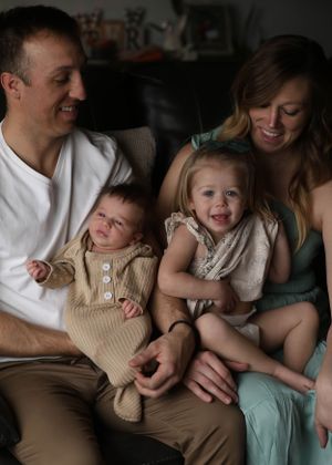 A happy family moment on the couch with everyone dressed in casual attire.