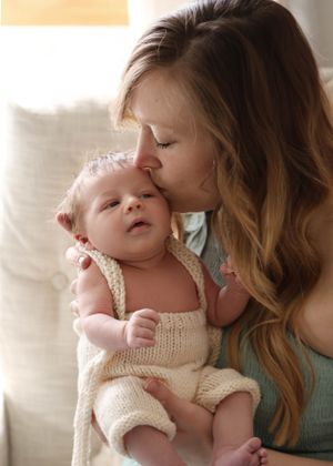 An intimate bonding moment between parent and baby in soft window light.