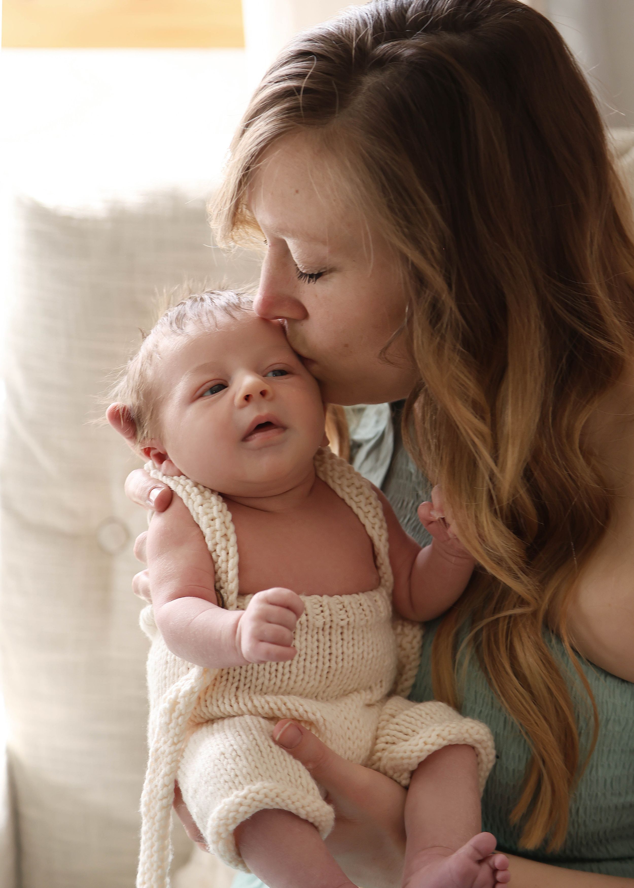 An intimate bonding moment between parent and baby in soft window light.