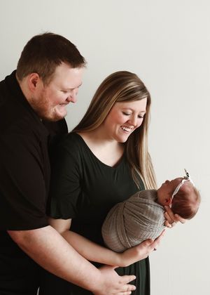 White studio portraits showing tender family moments with newborn in grey wrap.