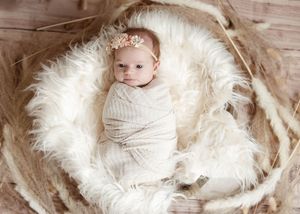 Progression of newborn photos on white furry backdrop with rustic wooden elements.