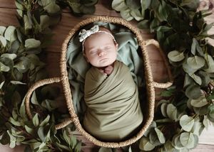 Artistic newborn photography series in basket with eucalyptus leaves and natural styling.