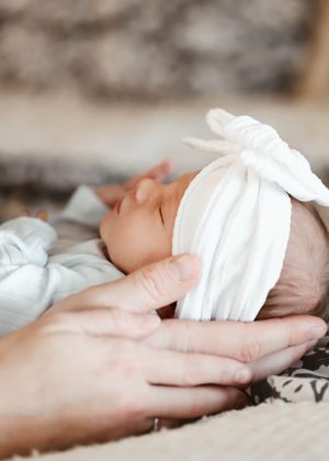 A sleeping infant rests peacefully in white clothing on a textured surface.