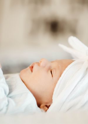 Profile view of a sleeping baby in white against a neutral background.