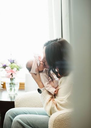 Tender family moments captured on a cream-colored couch near a window.