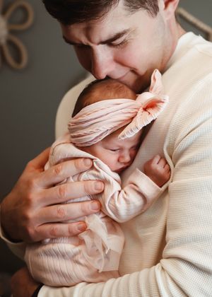 Tender moments captured of a baby being cradled in cream colored sweater.