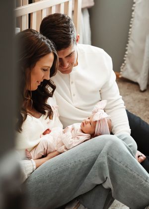 Parents in white and gray clothing share intimate moments with their newborn.