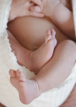 Close-up photos of tiny baby feet and toes wrapped in a white blanket.
