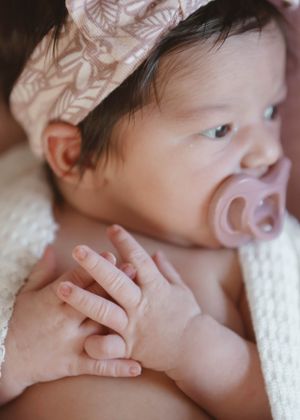 Close-up photos showing a baby's tiny hands and fingers against white fabric.