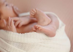 Detail shots of small baby feet against a soft pink background.