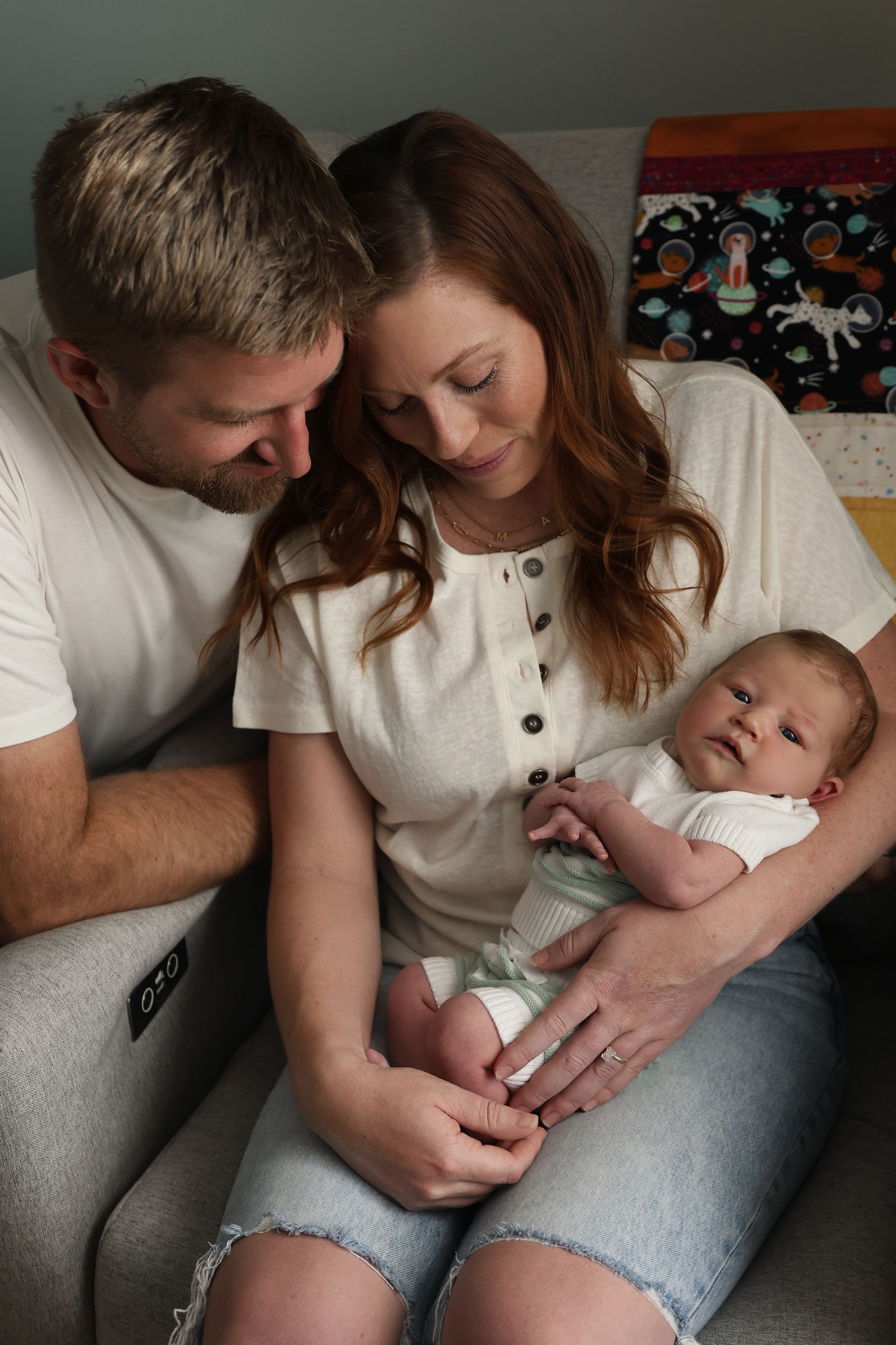 An intimate indoor family moment captured in soft lighting on a couch.