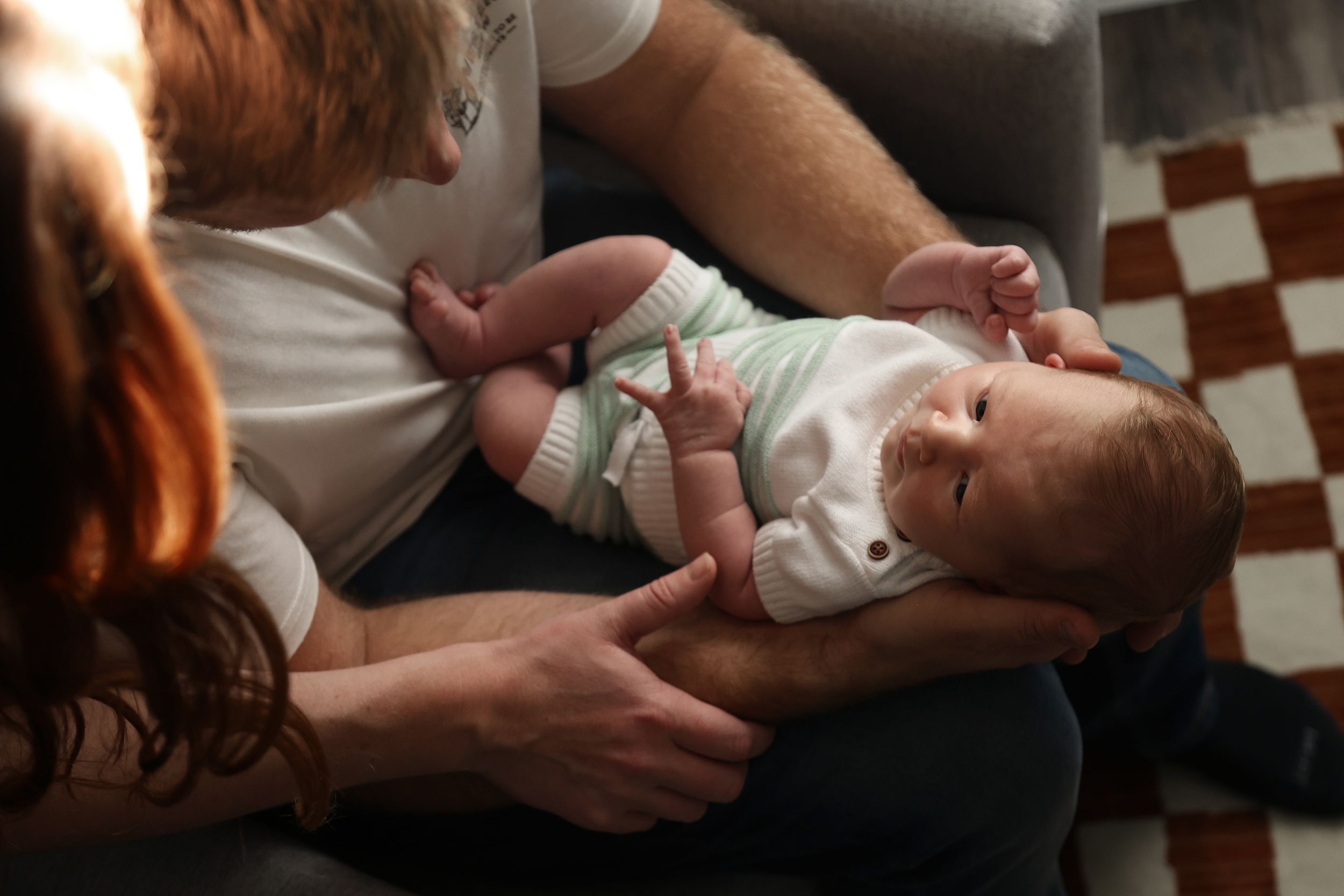 Intimate close-up shots of tender family moments in moody lighting.