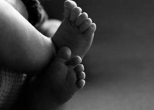 Close-up black and white photo of newborn baby feet, showcasing tiny toes and soft skin.