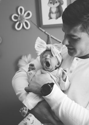 Sweet moments with a baby yawning while dad holds her captured in black and white.
