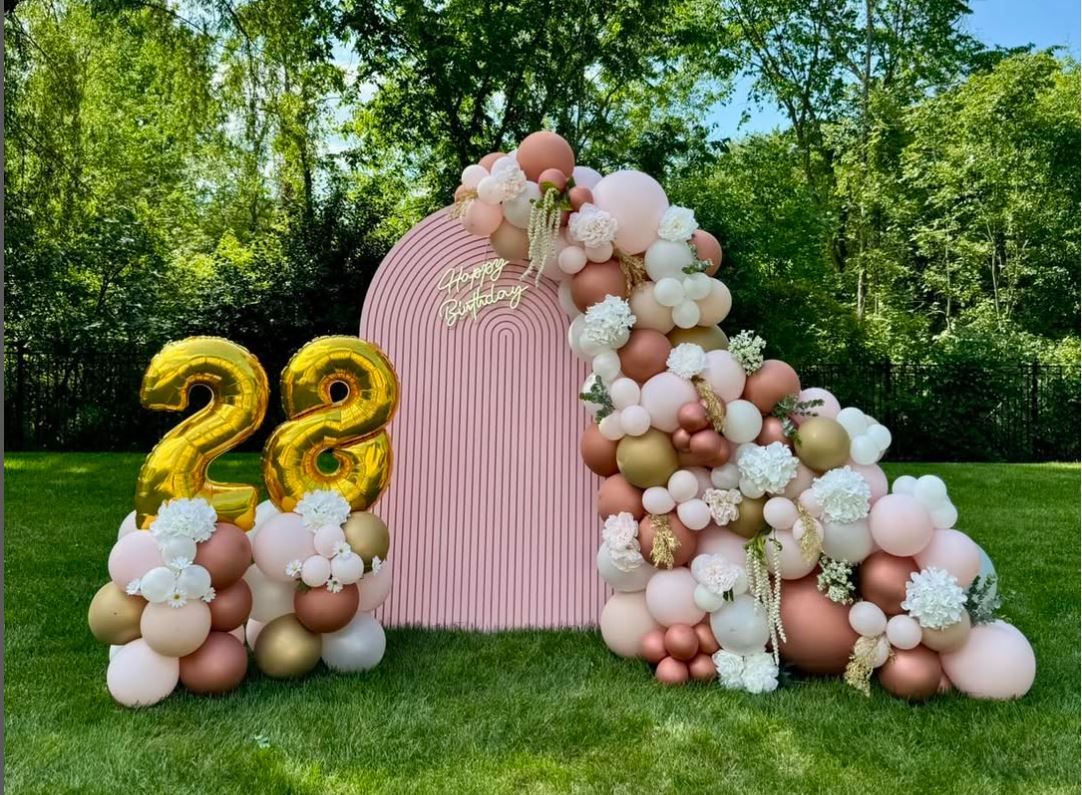 Pink and white balloon arch with gold number 22 decorations in a garden setting.