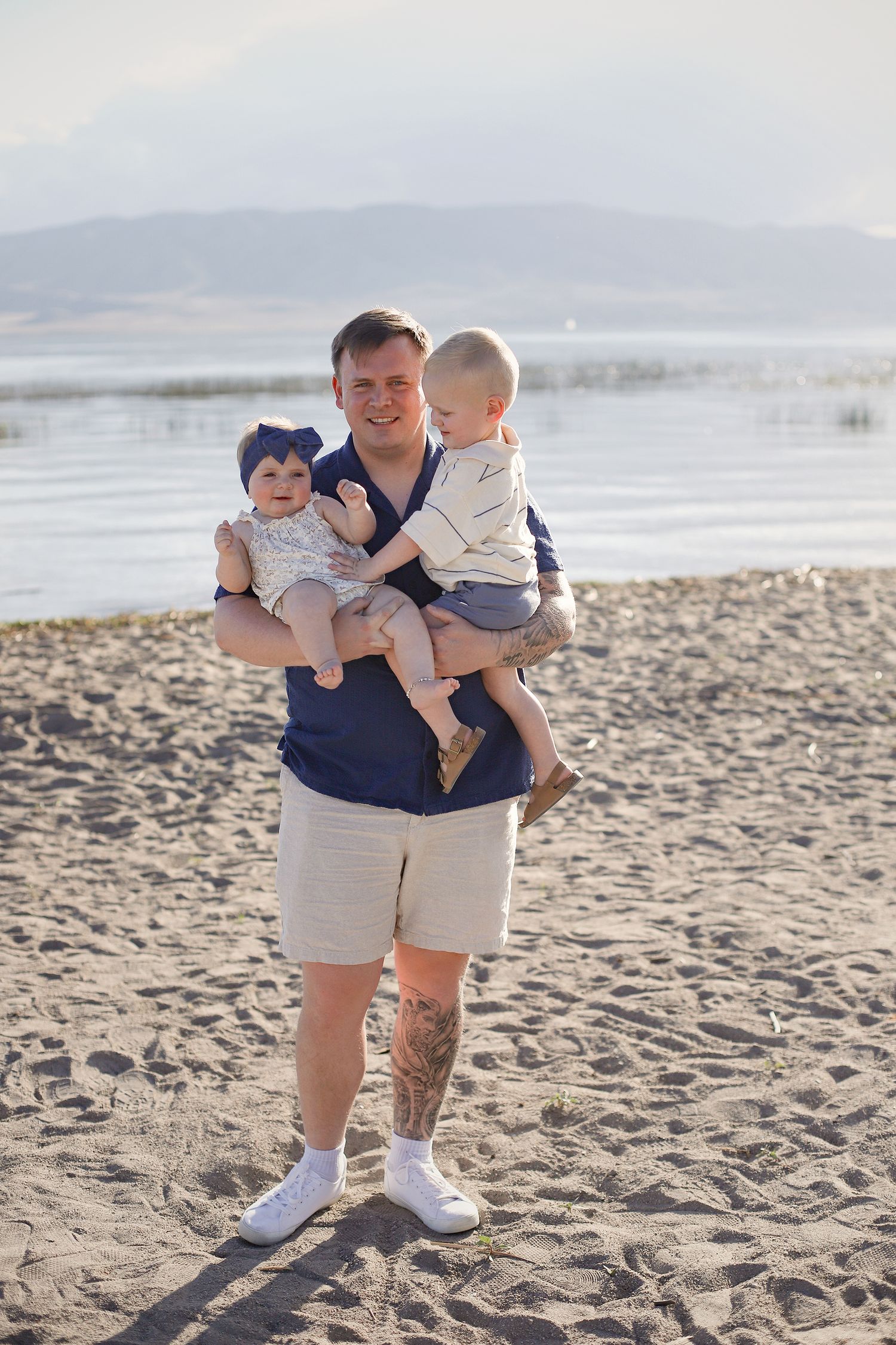 Family enjoying a sunny day together at the beach with mountains visible in the background.