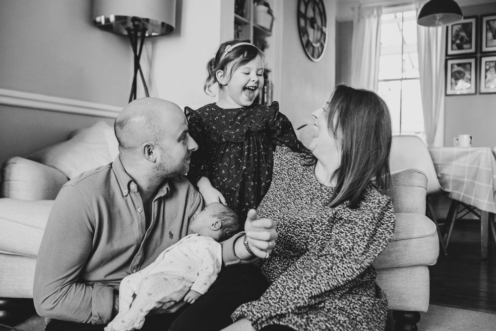 Black and white photo of a family having an intimate moment together on their living room couch.