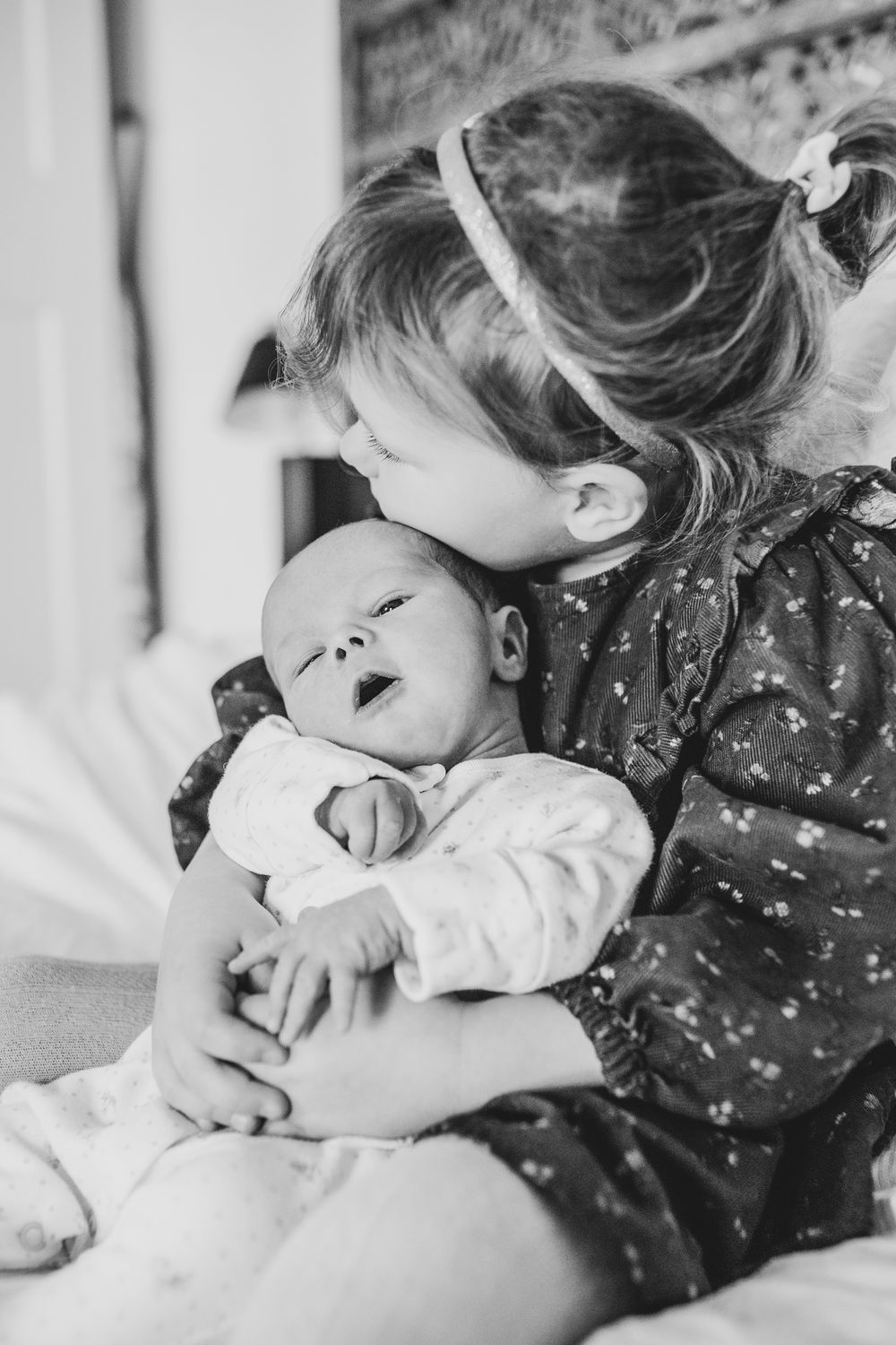 A heartwarming black and white photograph showing a tender moment of cuddles and laughter between two siblings.