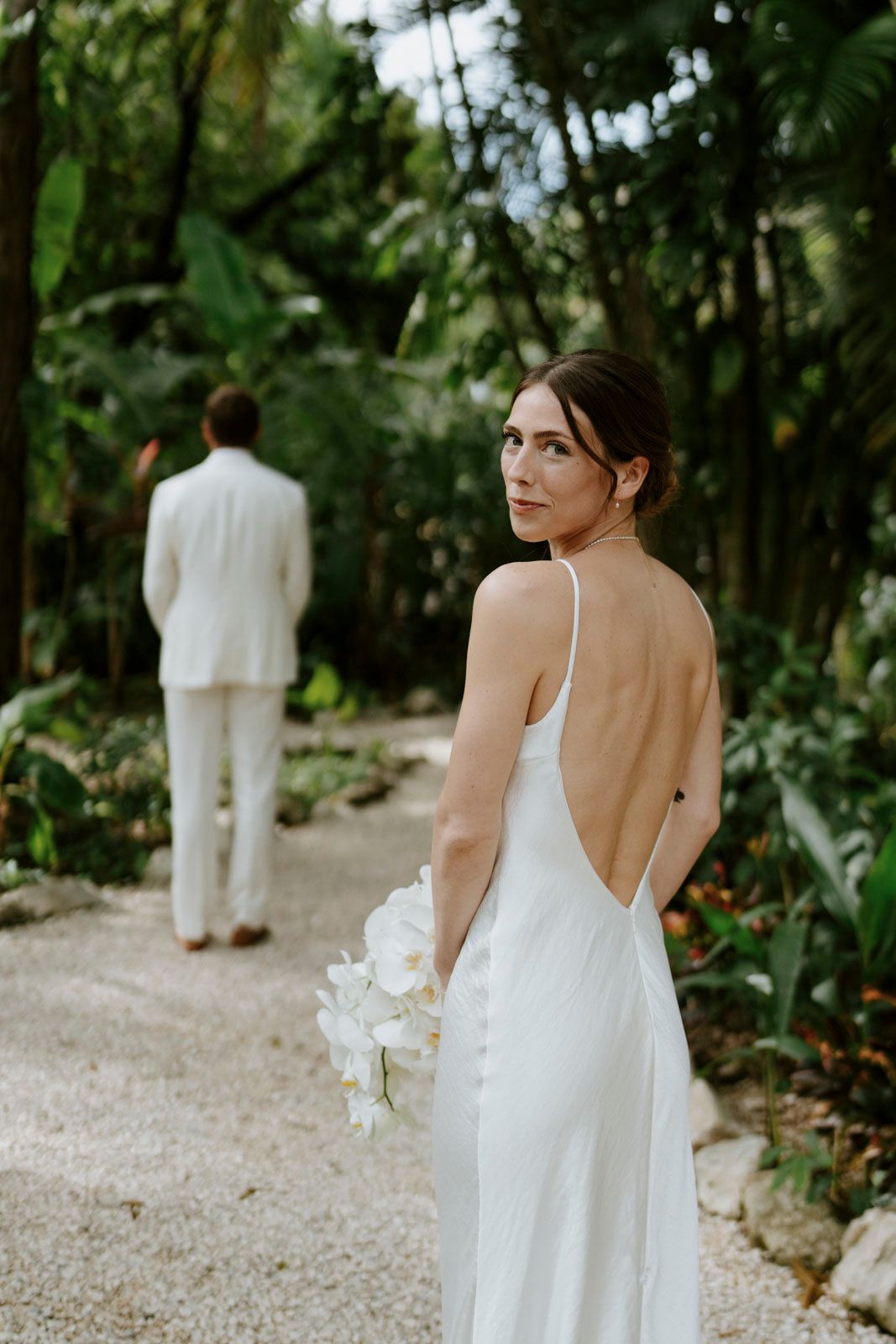 Bride walking toward her groom through tropical gardens in Nosara