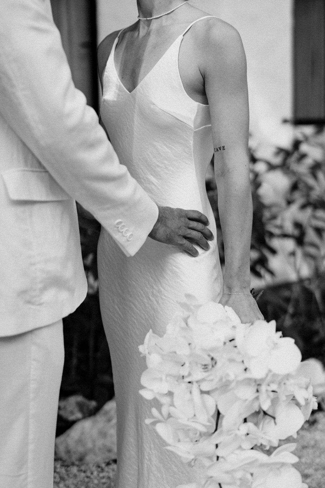 Groom holding the bride surrounded by greenery and soft light in Nosara