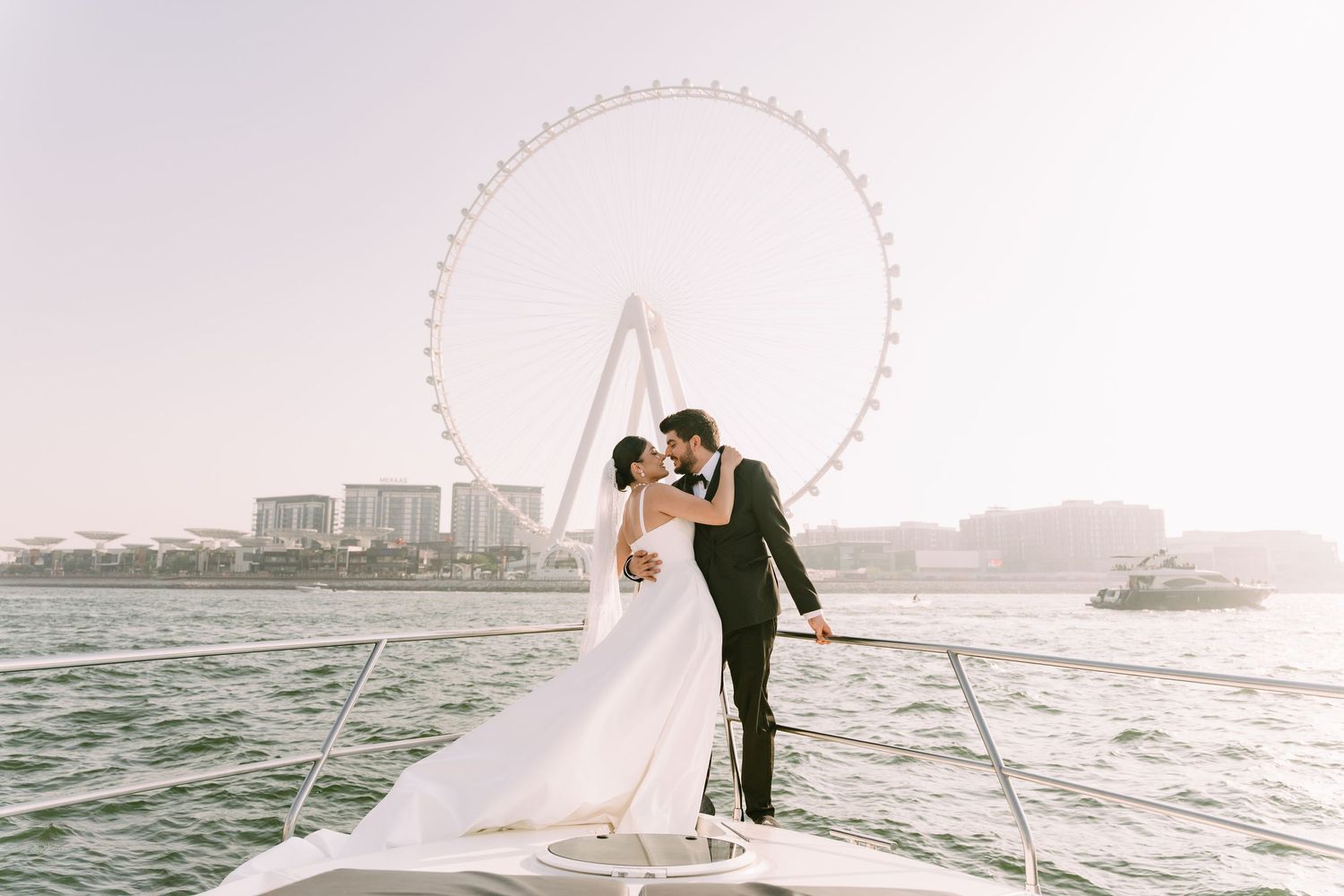 A bride in a flowing white wedding dress with an elegant veil blowing in the soft light of sunset.