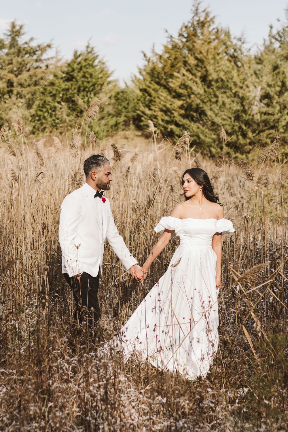 Romantic outdoor wedding portrait in tall grass with white off-shoulder dress.