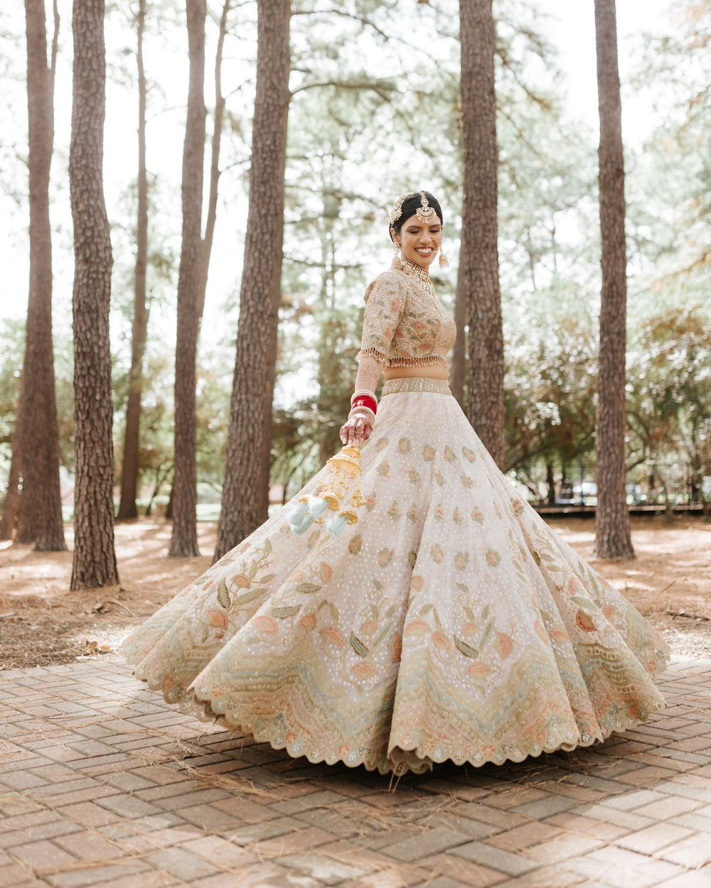 Traditional Indian wedding lehenga with intricate gold embroidery photographed in pine forest.