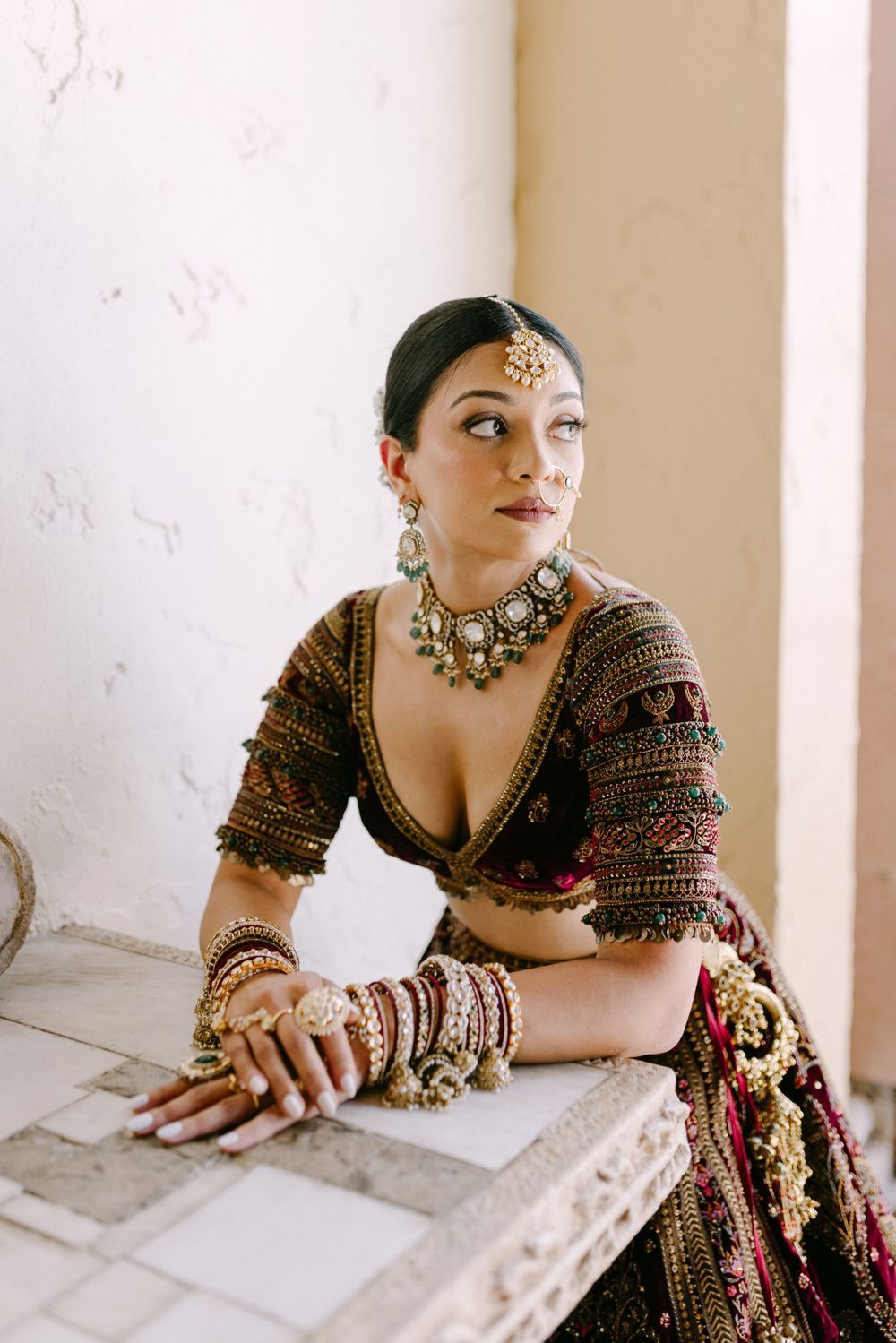 Traditional South Asian bridal portrait with ornate jewelry and embellished lehenga.