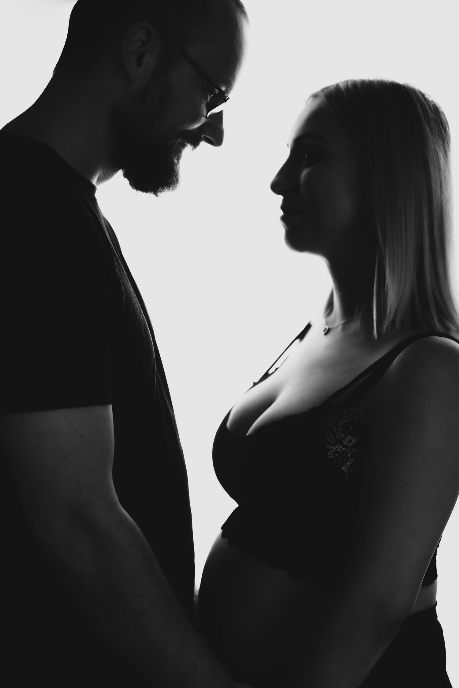 Black and white silhouette of expectant couple in intimate pose.