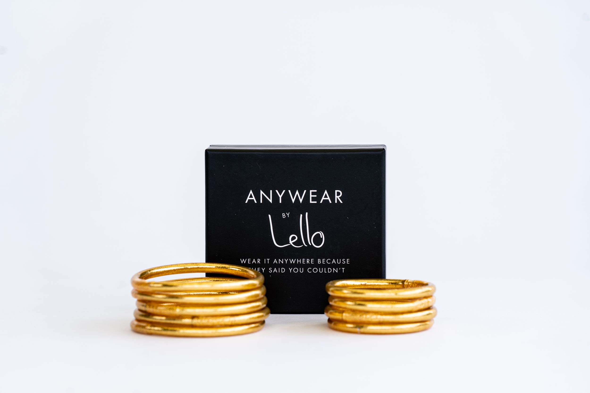 Black Anywear Lello box between two stacks of gold metallic bracelets.
