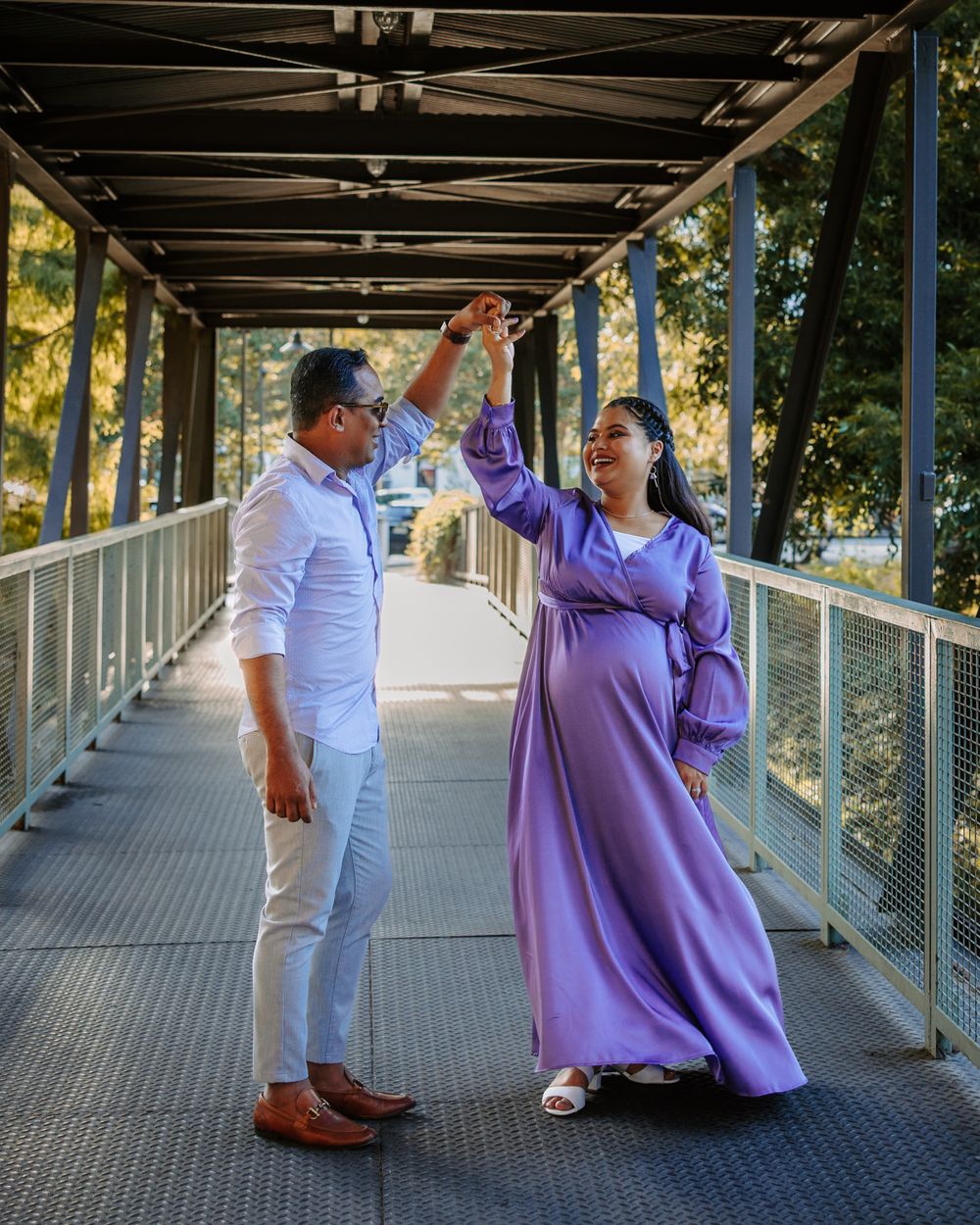 San Antonio Maternity Photography. A couple in white and purple attire celebrates on a covered bridge.