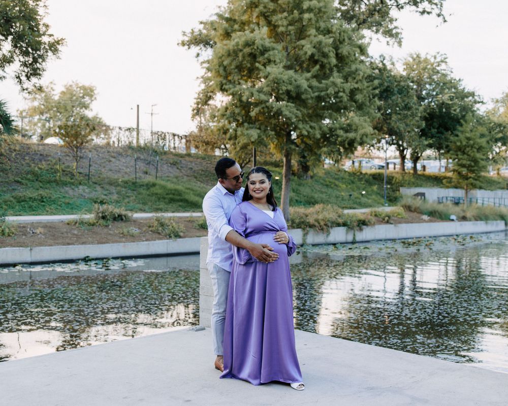 San Antonio Maternity Photography. A couple in coordinating outfits embraces by a pond during sunset.