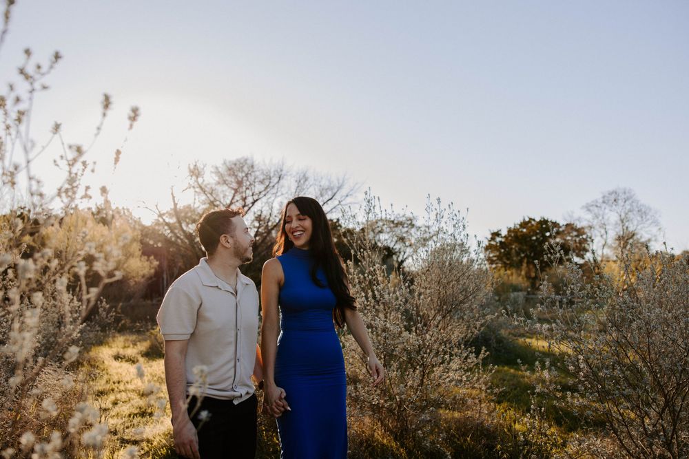 San Antonio Engagement Photography. Couple shares tender moment while walking through sunlit field at golden hour.
