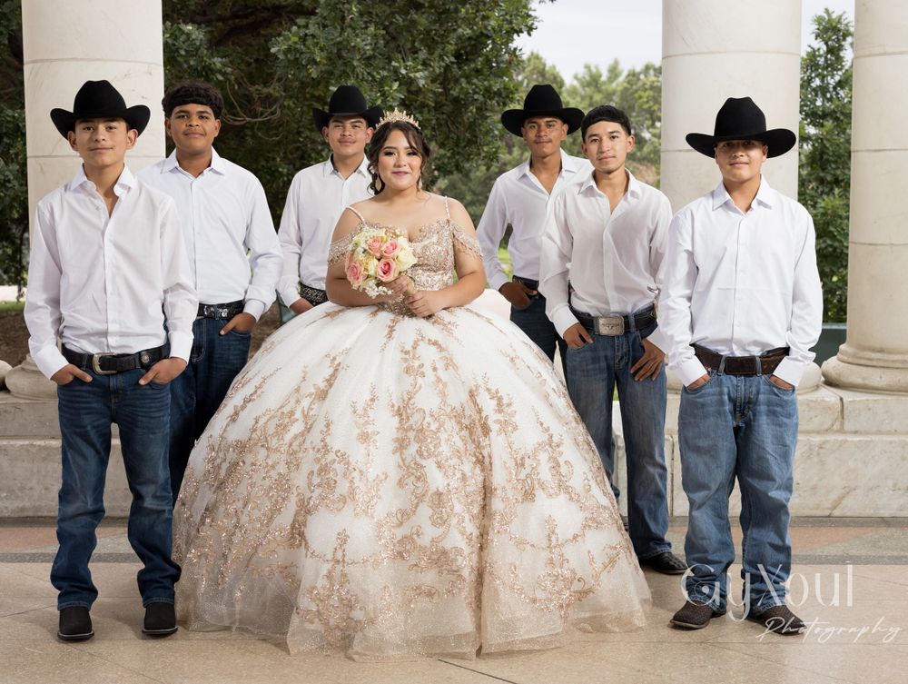Group photo showing a quinceañera dress with groomsmen in white shirts, jeans, and cowboy hats.