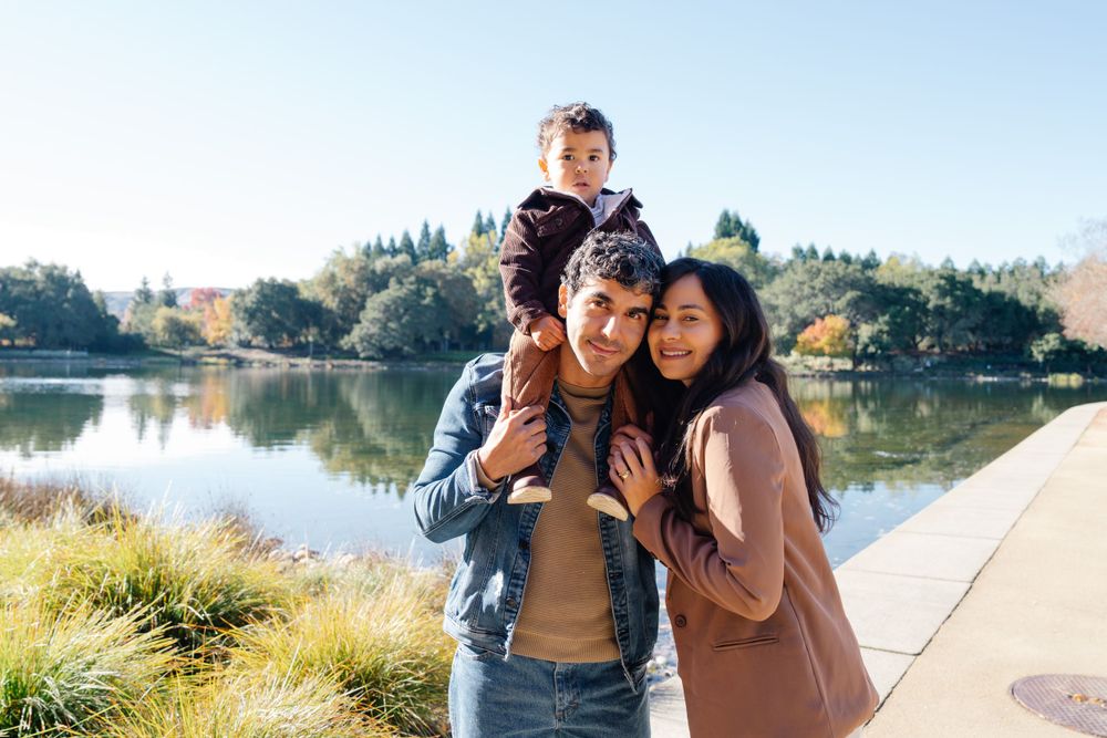 Family takes playful photo together by scenic lake on autumn day.