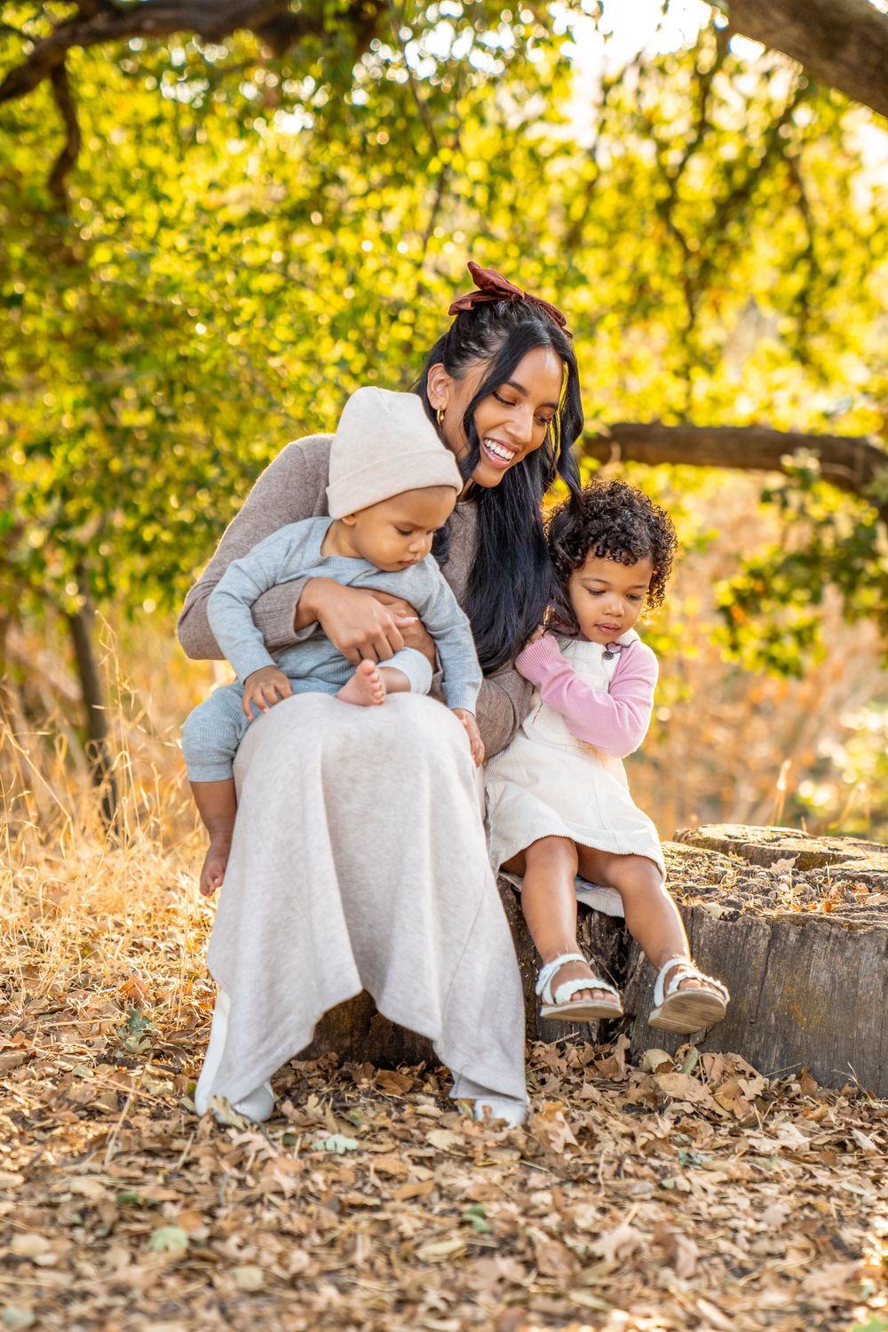 A heartwarming outdoor family portrait in autumn with golden sunlight filtering through trees.