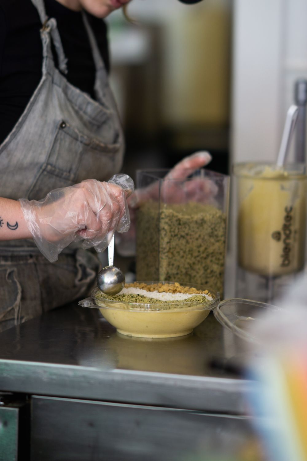 Hands preparing a creamy dessert by spreading custard mixture over a pastry base in a professional kitchen.