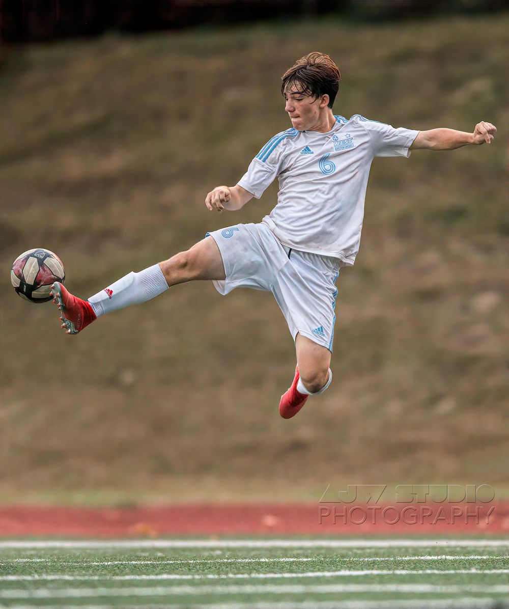 Soccer player executing an acrobatic kick while airborne on the field.