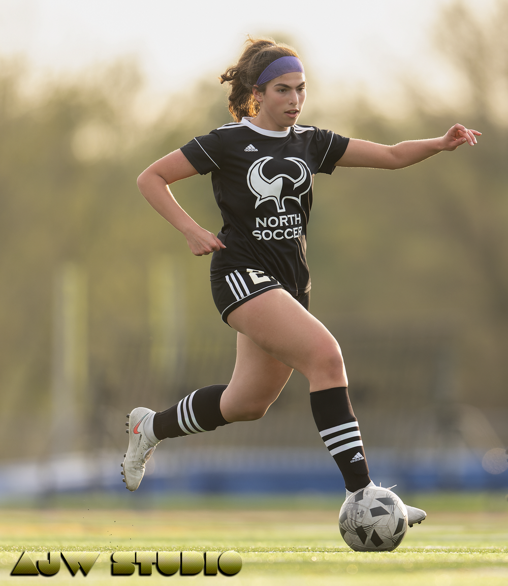Soccer player performing stylish ball control move during evening practice session.